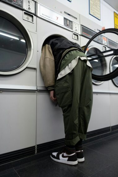 Person leaning into a washing machine while doing laundry in a laundromat.