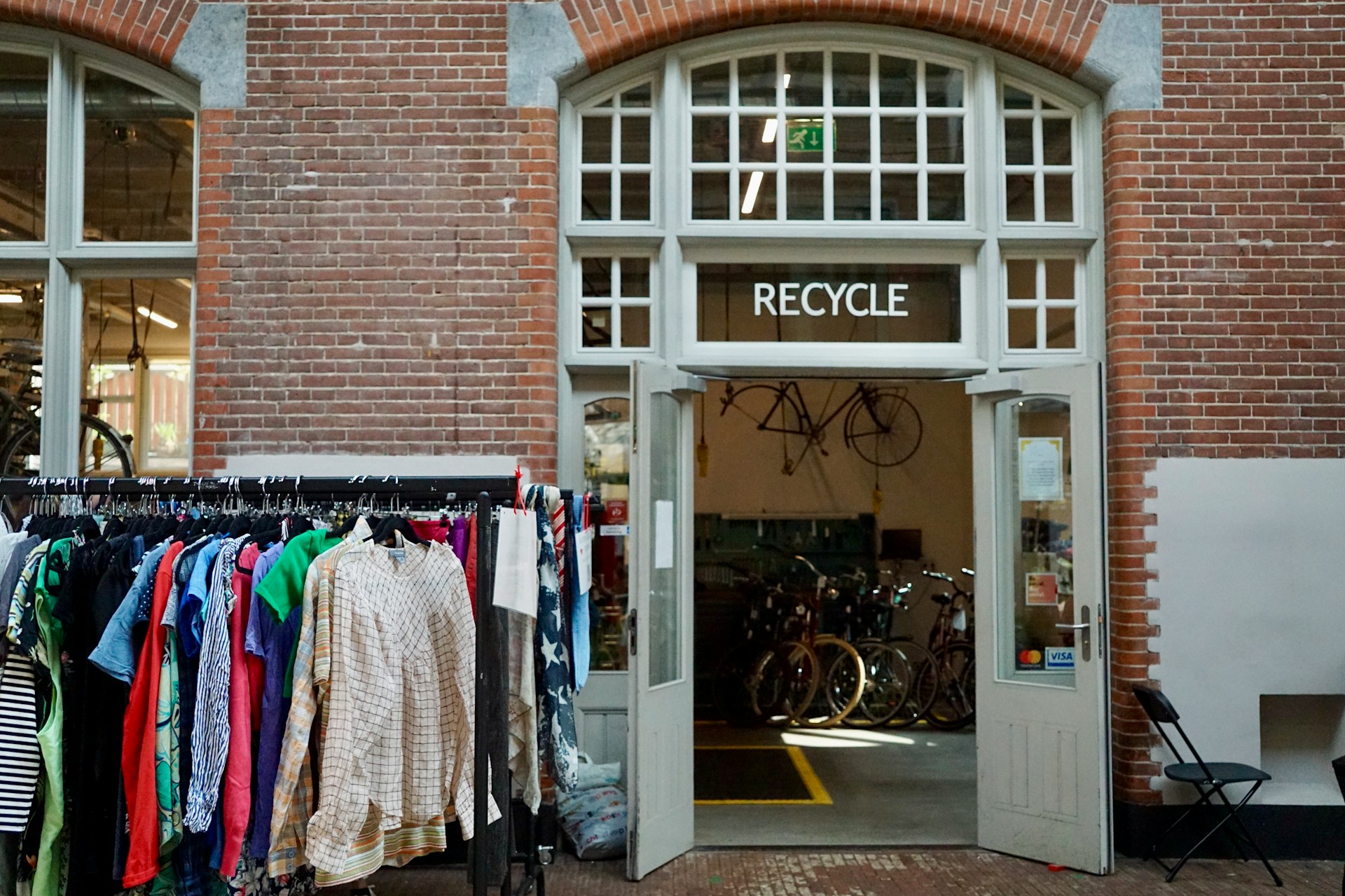 Clothing displayed outside a shop with the word “Recycle” above the entrance.