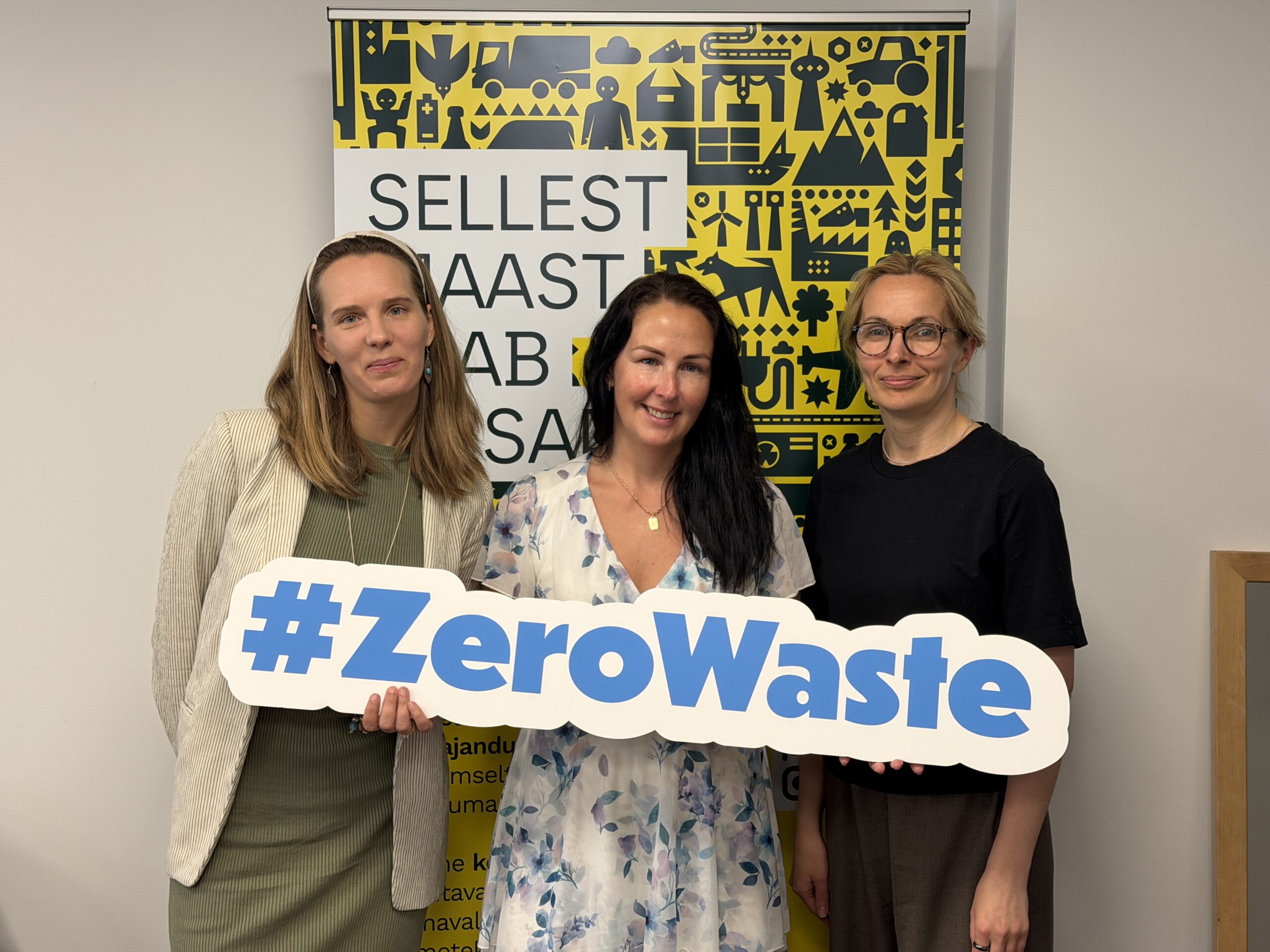 Three members of the Zero Waste Estonia team standing together and holding a Zero Waste sign